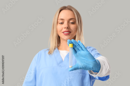 Nurse with test tube on grey background
