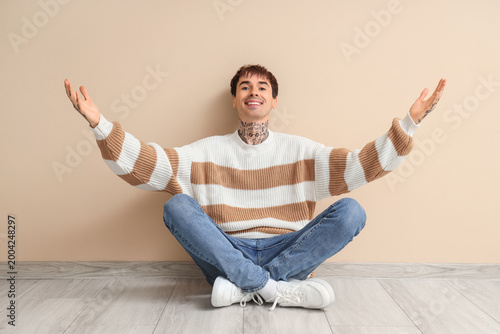 Young man opening arms for hug near beige wall