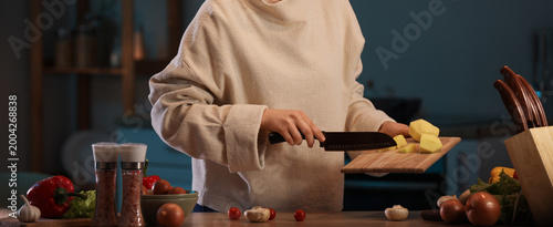 Young woman cutting potato ...