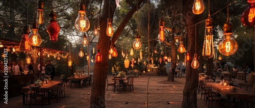 Dinner event with hanging lights at an outdoor restaurant in the evening near trees and guests seated at tables