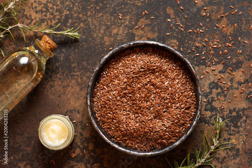 Flaxseeds in Bowl with Oil and Butter on Rustic Table
