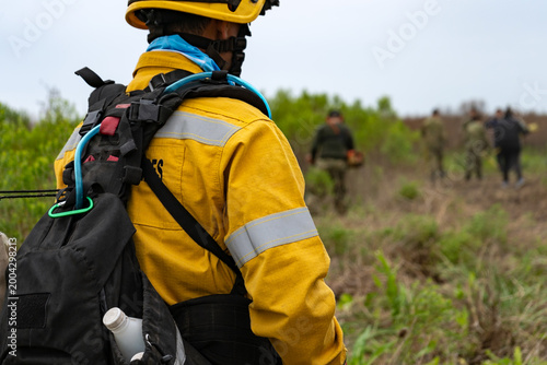 Bilde på lerret Wildland firefighter in yellow fire-resistant uniform with hydration pack lookin