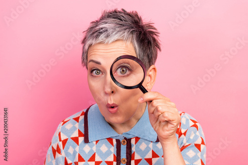 Schilderij op canvas Surprised woman with magnifying glass examining camera on pink background, playf