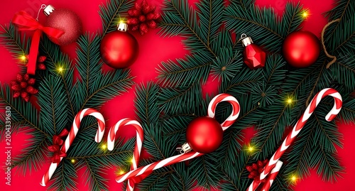 Cozy holiday flat lay with festive Christmas decorations and pine branches arranged beautifully on a red background.