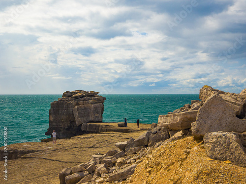 The distinctive massive rock formations towering along the coast with tourists taking pictures (Portland, England, United Kingdom)