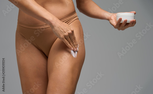Woman moisturizing leg skin with cream for hydration and body wellness