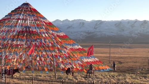 Impressive pennant play in the wind, like lung-than. Red flags and pennants in the form of a yurt. Urumqi city surroundings. Uighur Horsemen. Xinjiang Uygur Autonomous Region. China