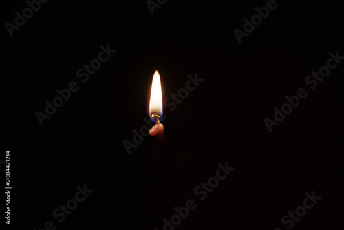 Burning candle flame in darkness minimal light concept