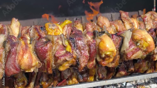 Delicious mixed meat cooking on rotisserie skewers over fire