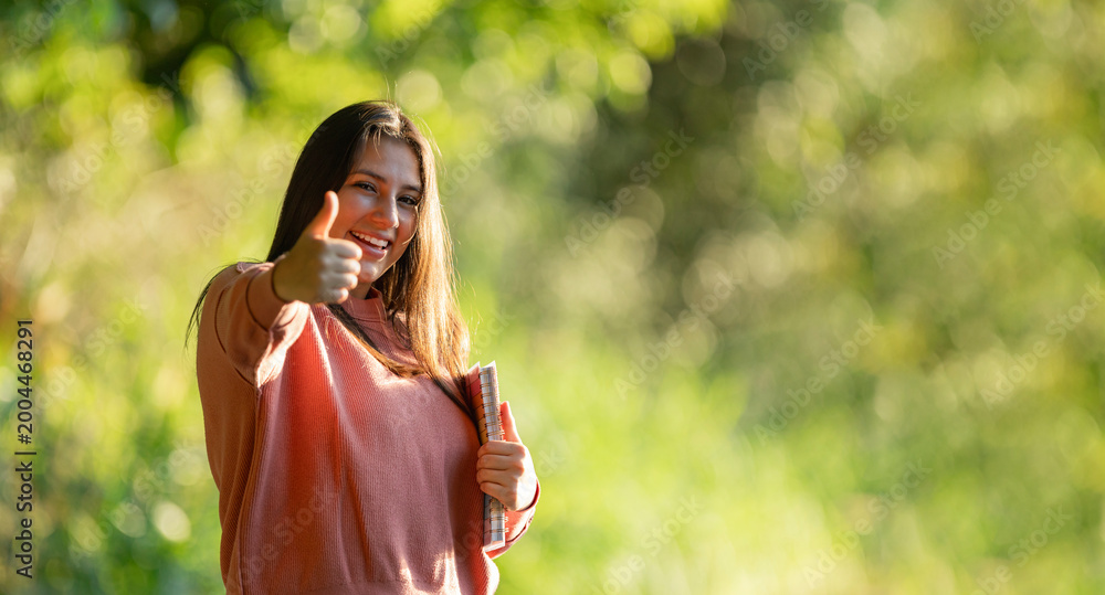Fototapeta premium Happy student giving thumbs up in park