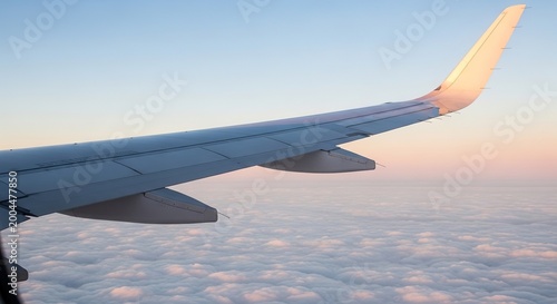 Airplane wing soaring above clouds at sunset
