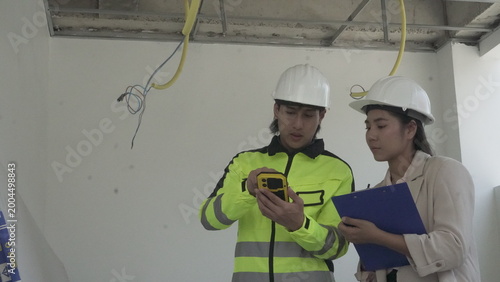 Electrician installing electrical wiring in building construction site with safety equipment