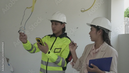 Electrician installing electrical wiring in building construction site with safety equipment