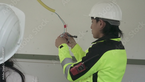 Electrician installing electrical wiring in building construction site with safety equipment