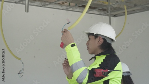 Electrician installing electrical wiring in building construction site with safety equipment