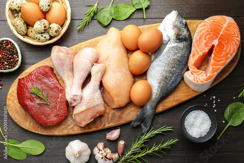 Foto Different types of fresh raw meat, fish, eggs and spices on wooden table, flat l
