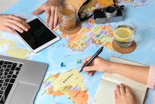 Top view of person hands pointing at world map, planning travel destination and vacation route