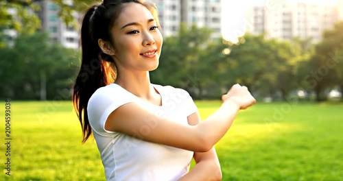 Asian woman in white tshirt smiling outdoors in a park with trees and buildings