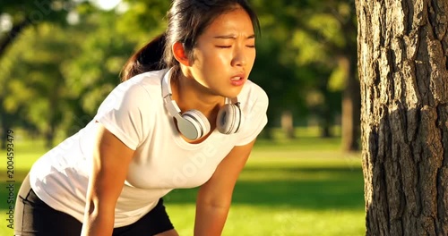 Young woman taking a break from running in the park outdoors