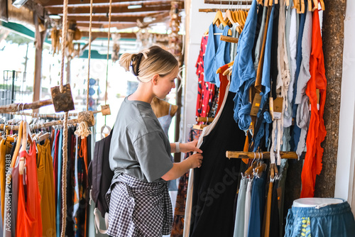 Quadro su tela Young woman choosing clothes in thrift-style boutique, conscious shopping, slow fashion, circular fashion, sustainable wardrobe and responsible consumption concept