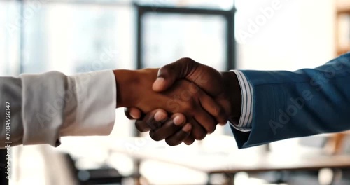 Two business people shaking hands in a modern office setting with blurred background