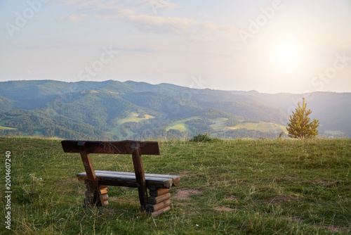 a wooden bench in the mountains invites to linger