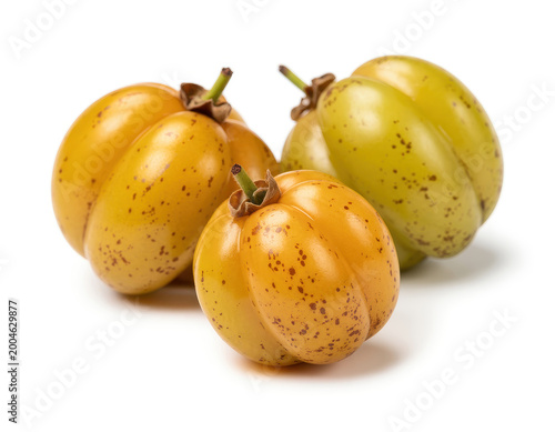 Three ripe yellow garcinia cambogia fruits with brown spots isolated on a plain white background