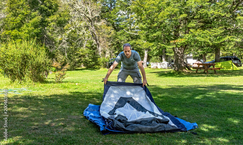 Adventurous man setting up a dome tent at Vuriloche camping site in Patagonia.