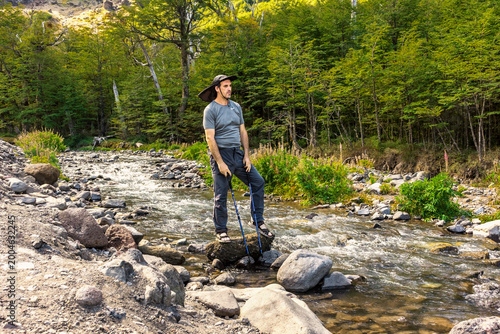 Active trekker using hiking poles to navigate a rocky glacial riverbed on Tronador approach trail.