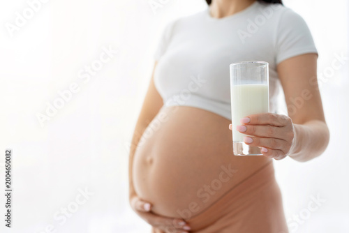 Εκτύπωση καμβά Closeup of pregnant woman holding glass of milk in hand, highlighting nutrition,