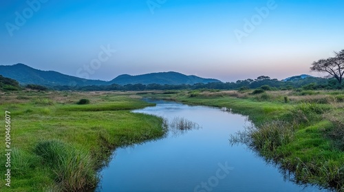 Peaceful River Reflecting the Soft Colors of Dawn Under a Clear Blue Sky With Distant Hills and Lush Greenery