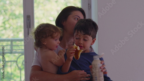 Photos Curly haired toddler quarreling with older sibling while mother holds both child
