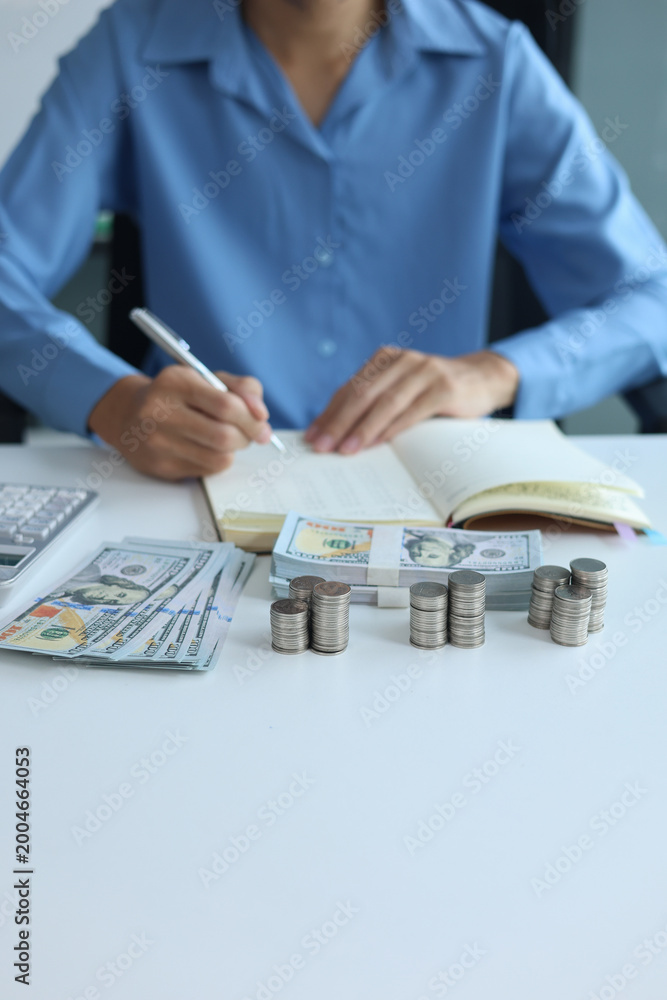Fototapeta premium Three stacks of coins arrange separated on the table while businessman writing in a notebook. Concept for financial planning or budgeting.