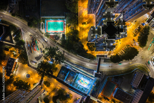 Brightly lit green football pitch next to a busy bus terminus at night in Hong Kong captures the vibrant energy of high density urban living.