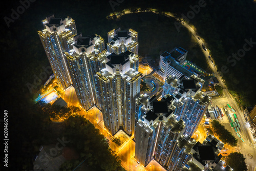 Stunning aerial night view of glowing high rise residential towers in Hong Kong showcases dense urban living and modern architectural scale.