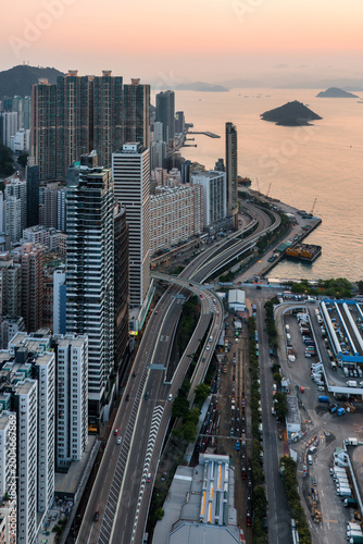 High-angle view of the bustling skyline and coastal highway in Hong Kong during the day, showcasing the city architectural scale and urban density.