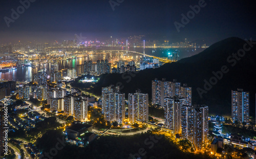 Modern skyscrapers and a busy container port glow under the night sky in Hong Kong, showcasing the city status as a global trade and finance hub.