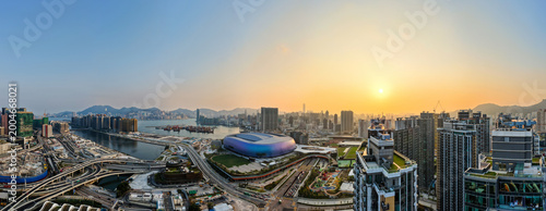 Panoramic sunset view over Kai Tak Sports Park and the dense urban landscape of Hong Kong showcasing modern architectural growth and coastal beauty.