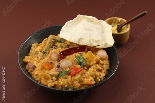 Traditional Tamil Nadu Sambar rice with mixed vegetables, dal, rice and served with ghee and Appalam