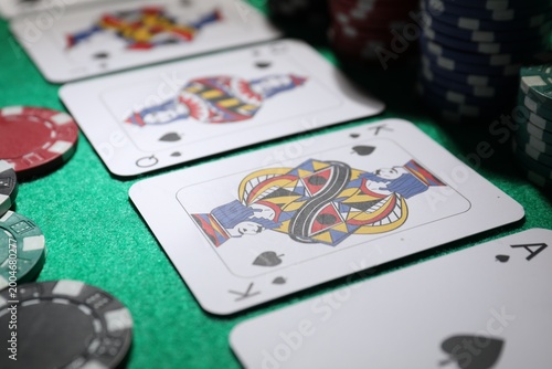 Foto Casino chips and playing cards on green table, closeup