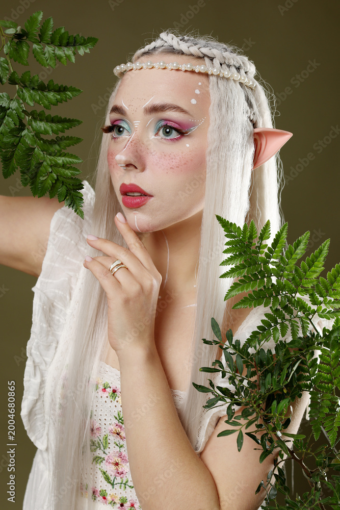 Fototapeta premium Beautiful elf girl with floral decor on dark olive background