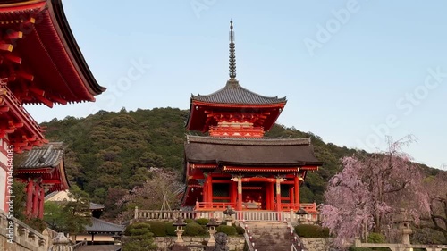 Kyoto, Japan - April 09, 2026: Vibrant orange temple structures and pagoda at the entrance of Kiyomizu-dera in Kyoto, with visitors walking through the historic hillside complex.