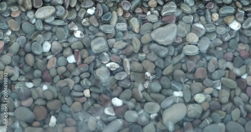 Calm ocean waves idyllic shore beach with turquoise water and pebbles, close-up of sea pebbles with calm sea waves