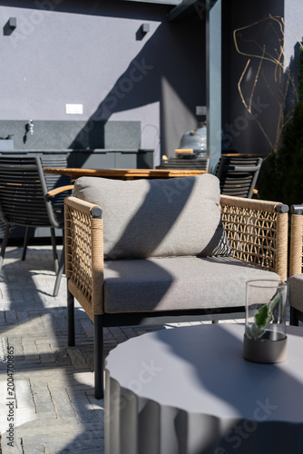 Tableau sur toile A modern sunlit patio lounge with a woven rope armchair and round coffee table o