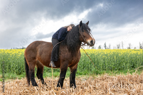 Frau mit Pferd vor Raps und Gewitterwolken