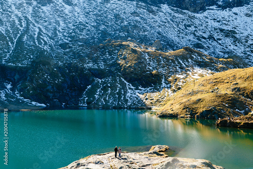 Active senior traveler, older woman with companion standing by scenic Balea Lake in Fagaras Mountains, Romania. Transfagarasan Highway. Travel concept