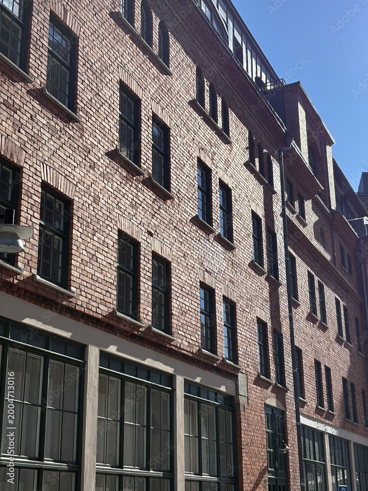 Fototapeta premium Historic Red Brick Building Facade with Black Windows Urban Street