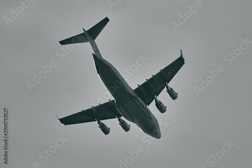 Low Angle Monochrome View of Military Cargo Plane Flying Overhead in Overcast Sky