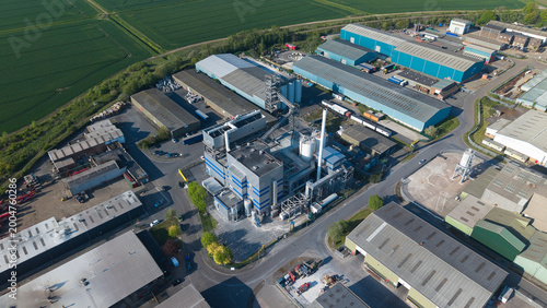 Aerial view of Flixborough Industrial Estate featuring large warehouses, factory structures, and silos surrounded by green fields under a clear sky in Flixborough, England, United Kingdom.