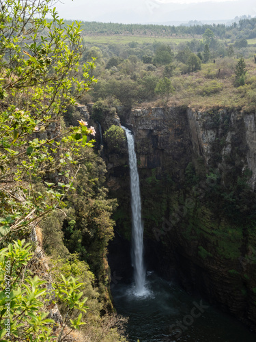 Scenic tall waterfall cascading into a natural pool surrounded by rocky cliffs and green vegetation, dramatic outdoor landscape and travel destination concept.